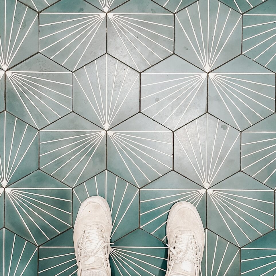 person wearing white shoes standing on white and brown floor tiles